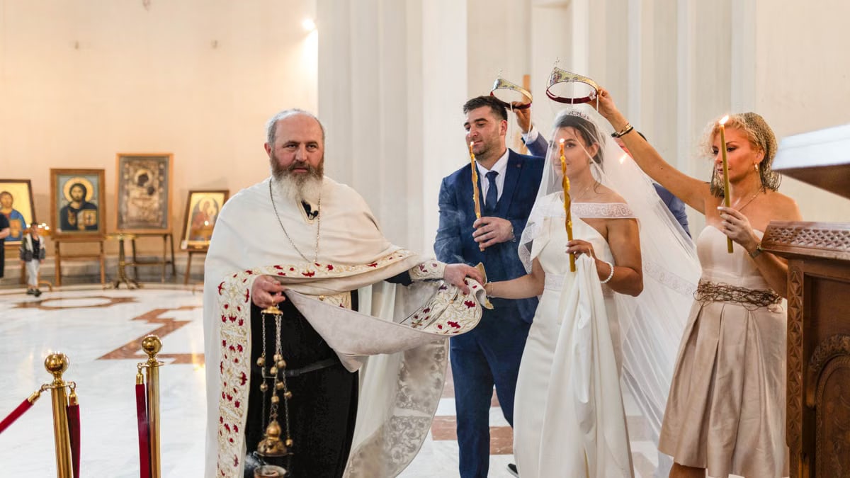 A traditional wedding ceremony with priest, bride, groom, and guests inside a church.